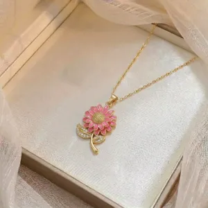 Vista detallada de collar dorado con colgante de girasol de esmalte rosa y circonitas.
