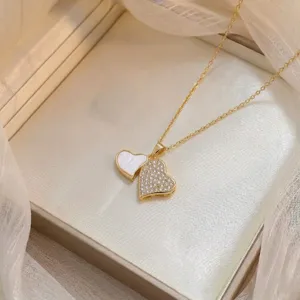 Detailaufnahme einer doppelten Herz-Halskette mit funkelndem Zirkon und weissem Inlay im Tüll.