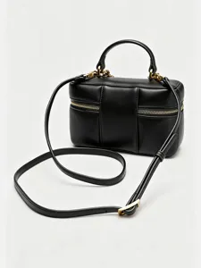 Detailed shot of a chic black leather vanity box bag with gold hardware and shoulder strap.