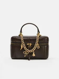 Detailed shot of trendy brown leather vanity box bag with chic gold chain and cute metal charms.