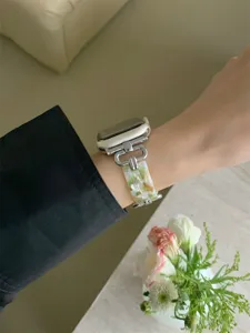 Gedetailleerd uitzicht op hars- en metalen horlogeband, elegante zilveren schakels en groen marmer.