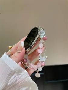 Vue détaillée du bracelet de montre connectée en perles avec cristaux roses et détails en métal.