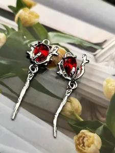 Gros plan de détail du pendentif rose en alliage de zinc avec un cristal rouge en forme de goutte.