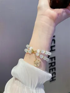 Gedetailleerde close-up van dubbellaags kattenoogsteen armband met schattige kattenbedel.