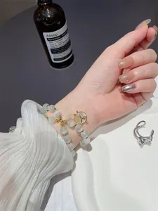 Prachtige meerlaagse kattenoog kralenarmband met charmante gouden hangerdetails.