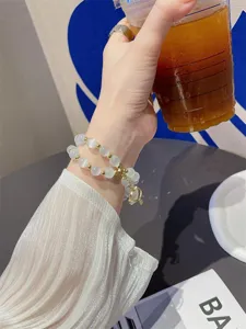 Gedetailleerd opname van een dubbele witte kattenoog kralen armband met goudkleurige metalen ballen.