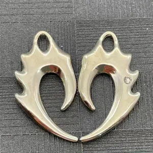 Vista detallada de colgantes de metal con diseño de llama y colmillo gótico con diamantes.