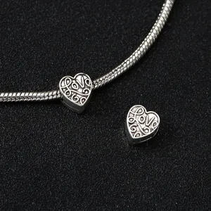 Nahaufnahme Detail von tibetischem Silber Liebesherz Charm und Schlangenkette DIY Schmuck.