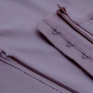 Close-up detail shot of skin-tone body shaper featuring secure zipper and hook closures.