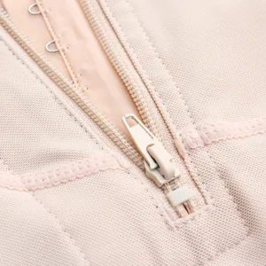 Close-up detail of beige shapewear showing zipper and hook-and-eye closure for body shaping.