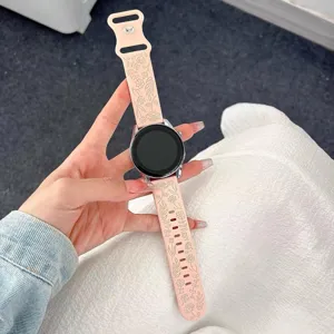 Dettaglio cinturino smartwatch in silicone rosa con elegante motivo floreale inciso e fibbia.