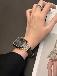 Detail shot of luxury rhinestone Apple Watch case and brown leather strap with sparkling diamonds.