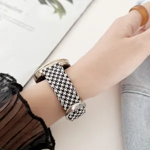 Detailed shot of a black and white houndstooth smart watch strap with metal buckle.