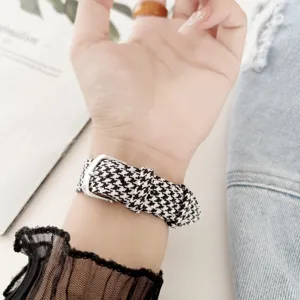 Houndstooth fabric watch strap detail close-up, stylish black and white pattern with metal buckle.
