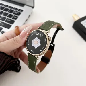 Close-up detail of green genuine leather smartwatch strap with gold buckle on white background.