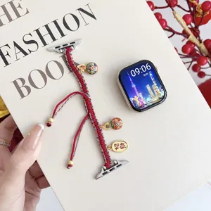 Detailed view of braided red watch strap featuring golden charms and cloisonne beads for smartwatches.