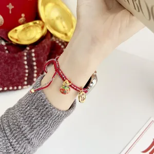 Red woven lucky rope bracelet featuring gold enamel charms and blessing coin pendant style.