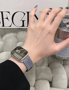 Gedetailleerde close-up van grijs suède smartwatch-bandje gedragen om de pols.