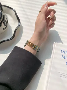 Nahaufnahme eines Vintage Jeans und Goldkette Apple Watch Armbandes, elegantes Accessoire.