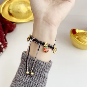 Close-up detail of the braided lucky rope bracelet with gold charm for watch accessory.