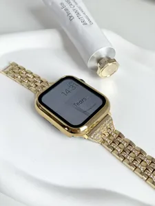 Detalle en primer plano de la lujosa caja de reloj dorada con strass y correa metálica.