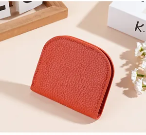 Detail shot of a compact orange leather wallet on a styled background with flowers.