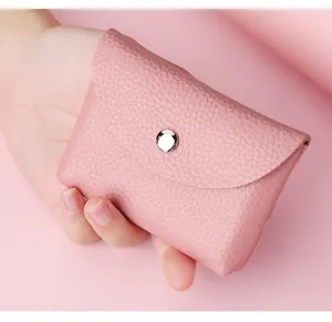 Détail en gros plan d'un mini porte-monnaie en cuir rose avec bouton-pression, compact.