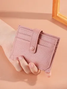 Minimalist pink leather card holder wallet featuring snap closure in hand, main view.