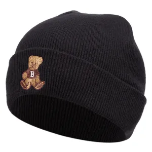 Close-up detail of the black knitted beanie showing the cute embroidered bear and soft texture.