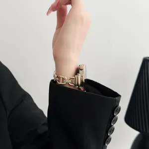 Primo piano elegante del cinturino per orologio in metallo dorato e strass al polso.