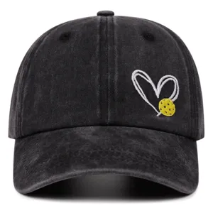 Close-up of black washed denim baseball cap featuring white heart and yellow pickleball embroidery.
