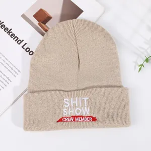 Detailed close-up view of the cozy beige knitted beanie showcasing cuff embroidery.