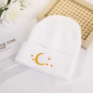 White knitted beanie hat with cute yellow moon and star embroidery for winter warmth.