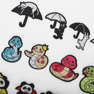 Detailed close-up of cute cartoon embroidered cat and snake patches for clothing repair.