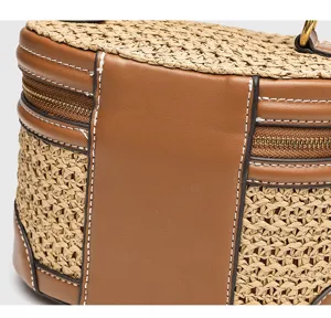 Detailaufnahme der Strohgewebe Box Tasche zeigt Lederverbindung und Metallreißverschluss Textur.
