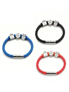 Close-up of braided leather bracelets with metallic castle and owl charms, magnetic clasp.