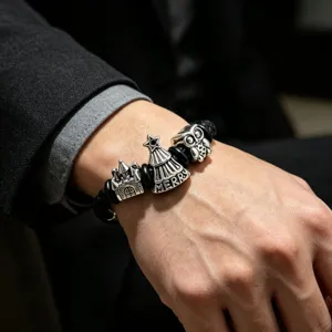 Men's leather charm bracelet detail, punk style silver metal beads on black braided band.