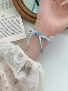 Bracelet tressé bleu et blanc avec charm papillon et perle en cristal transparent.
