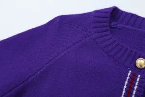 Detail shot of purple knit cardigan shoulder, collar, gold button, and striped placket trim.