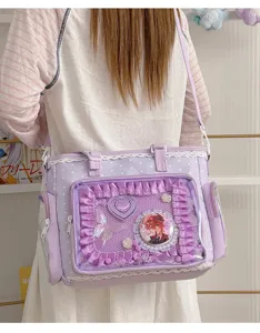 Vista dettagliata di una borsa ita viola chiaro con volant, finestra trasparente e spille anime.