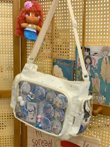 White canvas ita bag detail, transparent display window, cute anime badges, crossbody strap.