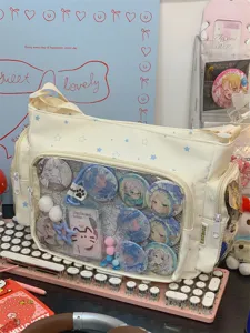 Detail view of beige canvas Ita bag with clear window displaying cute anime badges and charms.