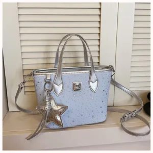 Borsa secchiello azzurra con stelle argentate, doppi manici e tracolla rimovibile.