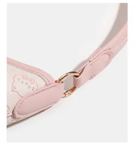 Pink leather handbag strap and cat embossed detail close up view showcasing quality hardware.