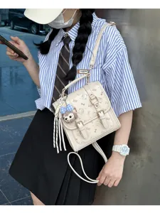 Detail shot of retro beige backpack with dual buckles and cute plush pendant in street style