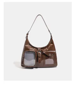 Brown patent leather shoulder bag detail showing clear window pocket and metal buckle clasp.