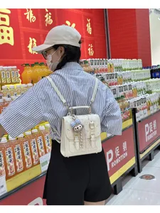 Detailed view of white mini backpack with cute plush charm, stylish commute daily bag in store.