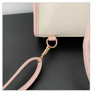 Close-up detail of women handbag strap connection with gold-tone hardware and pink leather.