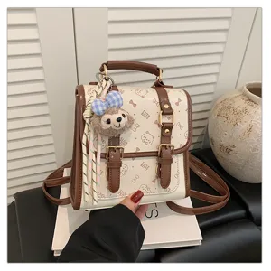 Detailed view of the college style PU leather mini backpack with cute plush charm and brown trim.