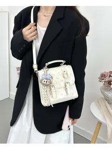 Detailed view of the stylish white mini backpack featuring cute cat prints and a fluffy charm.